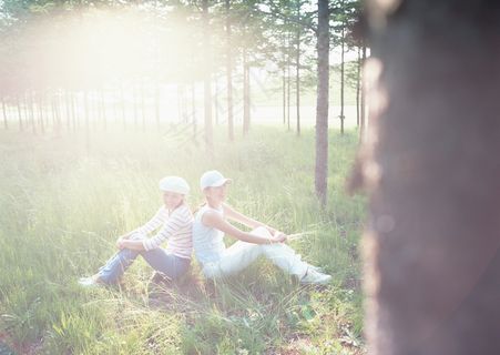 背靠背做在草地上的女人图片