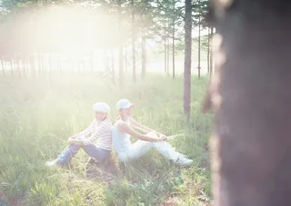 背靠背做在草地上的女人图片