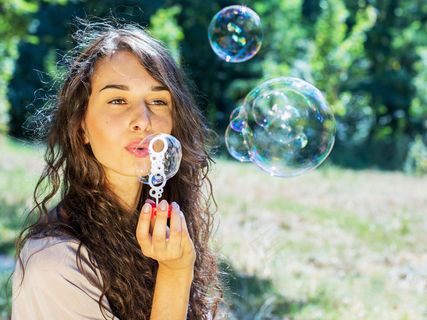 坐在草地上吹泡泡的美女图片