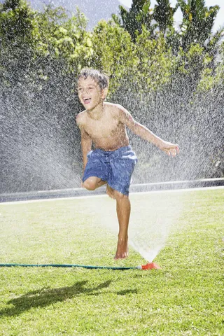 草地上玩水的小男孩图片