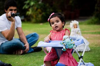 草地上的爸爸与学步车里的孩子图片