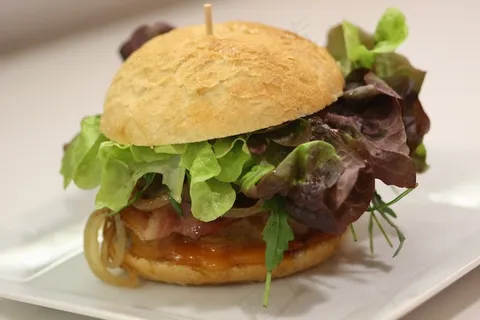 Hamburguesa Raza Nostra con Hoja de Roble,Rucola,Tomate,培根,Cebolla Braseada和Queso Chedar Hamburguesa Raza Nostra con Hoja de Roble,Rucola,Tomate,培根,Cebolla Braseada和Queso Chedar
