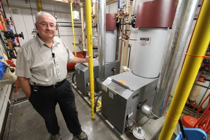 落基山山脉学区的设施经理Ken Riordan展示了劳伦斯·格拉西学校的两台高效燃气冷凝锅炉，这只是众多使该学校非常节能的智能，肉类和土豆特色之一。