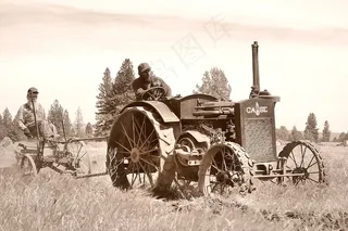 威利和儿子在古董Case拖拉机后面开着古董犁