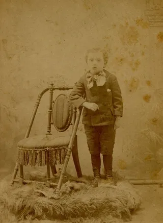 男孩与椅子和羊毛地毯摆姿势