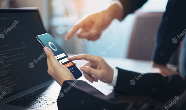 智能手机上的女商人和团队设计应用程序