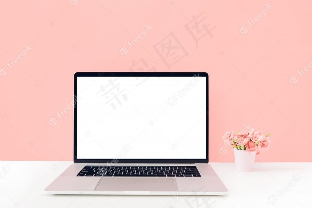 带白色空白屏幕的笔记本电脑，桌上有花瓶