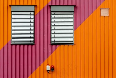 橙色和紫色金属墙的背景是白色的百叶窗