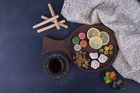 厨房毛巾上放着糖果和一杯茶的木制小吃盘