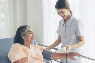 护理人员在病床上测量老年妇女的血压-医疗保健老年概念