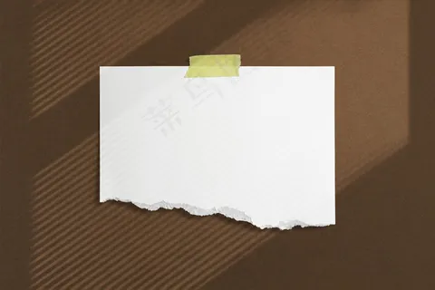 用胶带将空白撕破的纸框粘在棕色纹理的墙上，带有柔和的窗影土坯