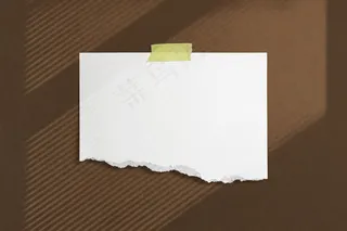 用胶带将空白撕破的纸框粘在棕色纹理的墙上，带有柔和的窗影土坯