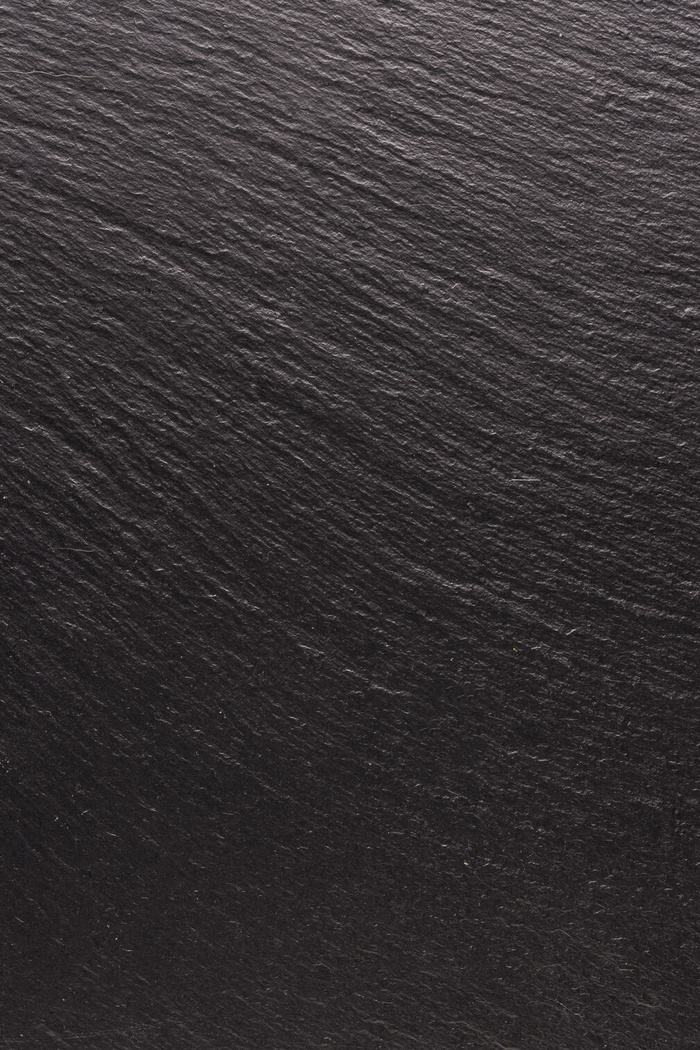 黑色石头，纹理为背景。平滑结构表面上的阴影和灯光