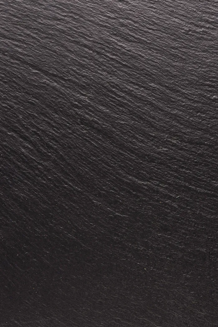 黑色石头，纹理为背景。平滑结构表面上的阴影和灯光