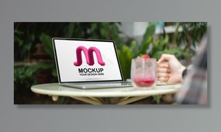 女自由职业者拿着一杯饮料放在桌上，手里拿着电脑模型样机