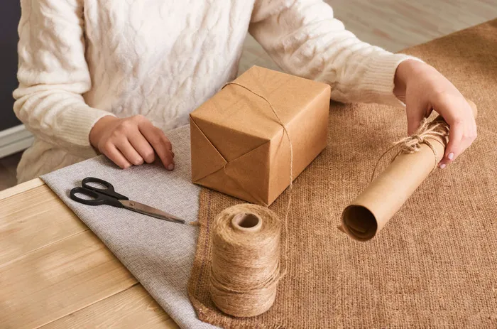 重点放在女人手上的白色针织毛衣包装盒里。手工包装纸和天然绳线。节日礼物，惊喜。节礼日礼物