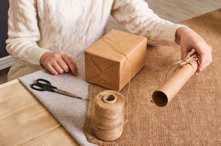 重点放在女人手上的白色针织毛衣包装盒里。手工包装纸和天然绳线。节日礼物，惊喜。节礼日礼物