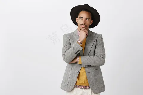 努力寻找解决办法，让生活更美好。身着时尚服饰，头戴黑色帽子，目光集中，富有魅力的非洲男性，抚摸着下巴，抬起头，表情深思熟虑，思考或回忆重要事件