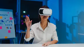 年轻的亚洲女设计师在现代创意家庭办公之夜使用vr眼镜（虚拟现实）测试手机应用程序开发软件。社会隔离，隔离以预防冠状病毒。