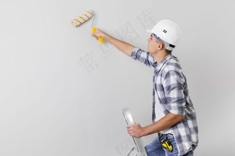 一名男子拿着有复印空间的油漆辊的中镜头