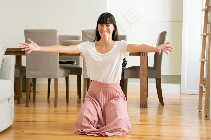 微笑的女人为孩子们摊开双手，跪在客厅里。