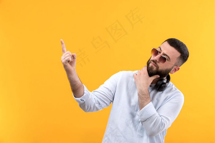 年轻人穿着白衬衫，留着胡子，戴着墨镜，戴着黑色耳机