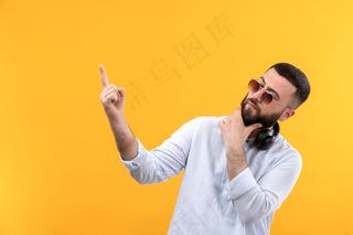 年轻人穿着白衬衫，留着胡子，戴着墨镜，戴着黑色耳机