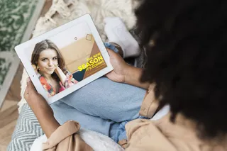 女性坐在沙发上，手上拿着平板电脑，过肩射击