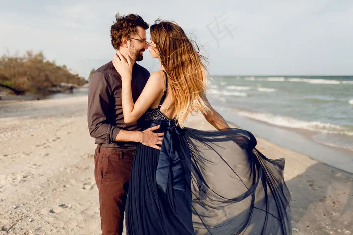 浪漫的时刻，美丽的夫妇，时尚的女人和男人在海边户外摆姿势。令人惊叹的蓝色连衣裙和休闲装。蜜月假期。
