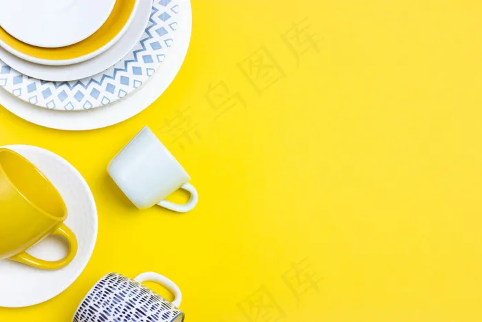 很多不同的陶瓷盘子，空咖啡对，盘子，杯子在亮黄色的背景上。抽象装饰物