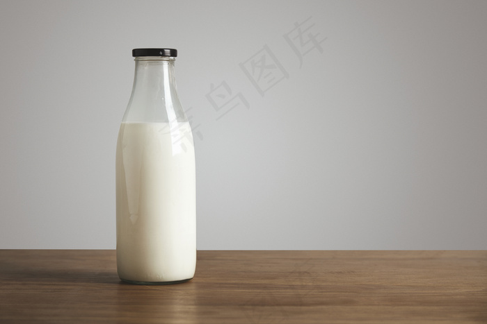 简单的老式瓶装满了厚木桌上的新鲜牛奶。用黑色帽子封闭。咖啡店
