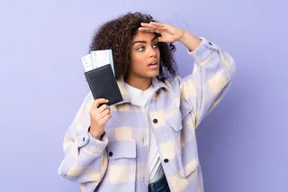 一位年轻的非洲裔美国妇女在度假时拿着护照和机票在远处寻找