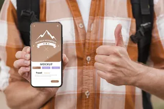 笑脸男手持智能手机，在野营时竖起大拇指的前视图