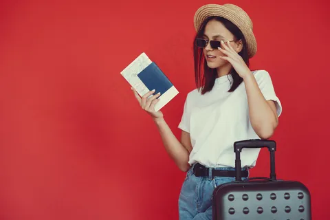 红墙上摆着旅游设备的时髦女孩 红墙上摆着旅游设备的时髦女孩