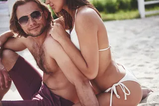 在海滩上穿着泳装的漂亮性感情侣。浪漫地躺在沙滩上。