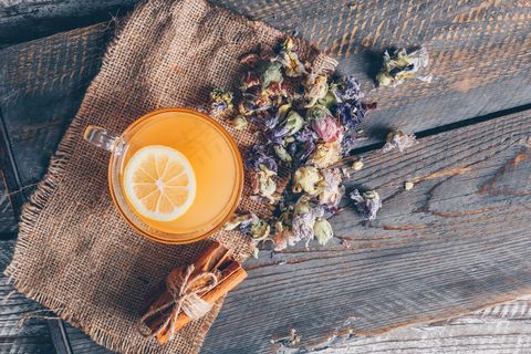 顶视图橙色水杯，柠檬和茶类，布袋布和深色木质背景。水平的