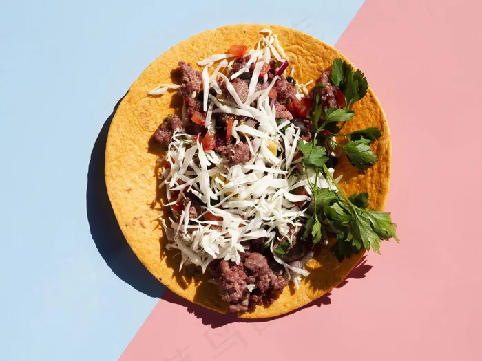 美味的墨西哥玉米卷配肉和蔬菜，背景为蓝色和粉色
