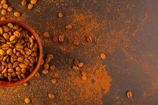 在棕色背景的棕色盘子里的咖啡籽的俯视图