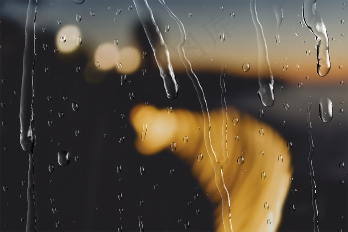 散景灯在晚上通过窗户与雨滴