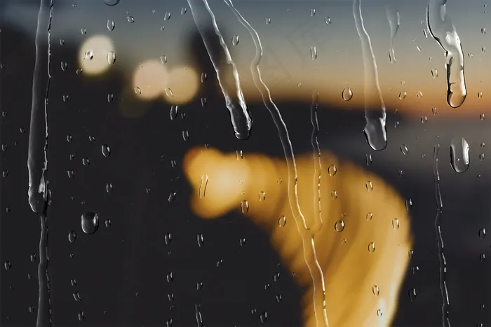 散景灯在晚上通过窗户与雨滴