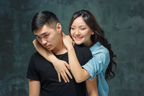 灰色摄影棚背景上微笑的韩国夫妇的肖像 灰色摄影棚背景上微笑的韩国夫妇的肖像