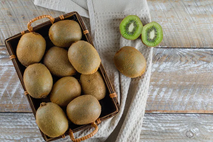 篮子里的猕猴桃放在木制和厨房毛巾上。平躺。