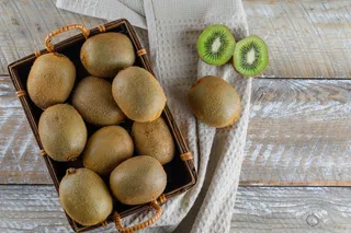 篮子里的猕猴桃放在木制和厨房毛巾上。平躺。