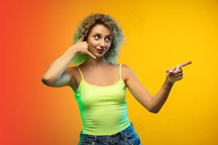 白种年轻女子的画像孤立在渐变工作室背景霓虹灯。漂亮的女性卷发模特，休闲风格。