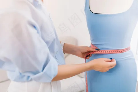 这是一幅画面,主要内容集中在一个女孩的手上,她在模特身上试穿衣服。这幅画是在工作室里拍的。 这是一幅画面,主要内容集中在一个女孩的手上,她在模特身上试穿衣服。这幅画是在工作室里拍的。