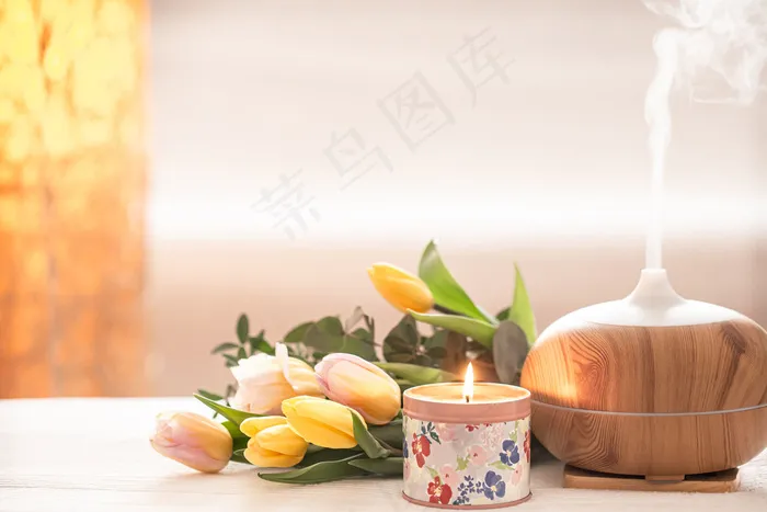 桌上的芳香油扩散器灯上模糊着一束美丽的郁金香和燃烧的蜡烛。