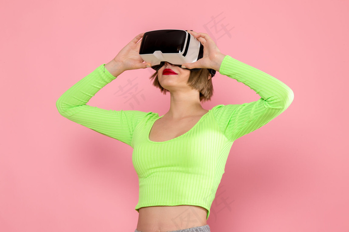 穿着绿衬衫和灰色裤子的年轻女子在尝试虚拟现实游戏