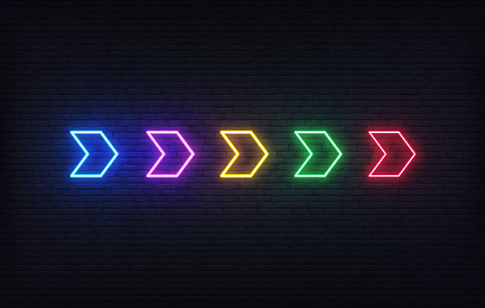 霓虹箭头。砖墙背景上的一组五颜六色的未来主义发光霓虹箭头指针。