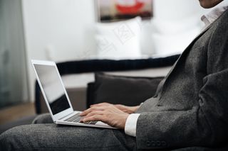 穿着西装的商人膝上放着一台笔记本电脑