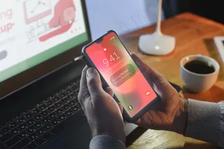 在办公桌上拿着智能手机的男人的高角度